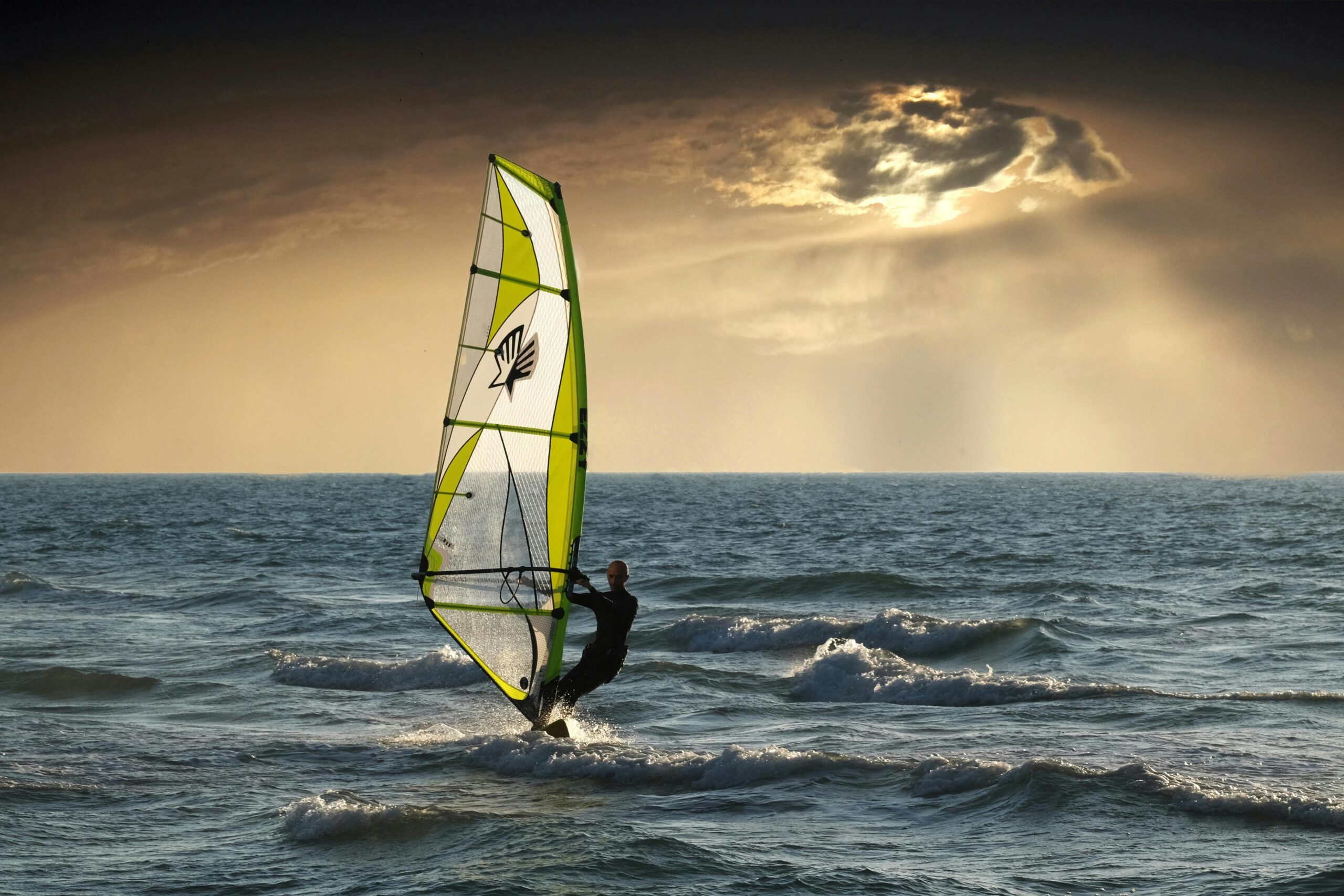Exciting windsurfing action against a dramatic sunset seascape. Perfect for adventure and travel themes.